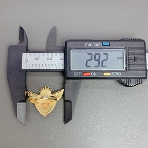 Macro view of gold winged heart ring measurement with a digital caliper showing size details