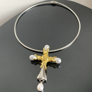 Close-up of vintage mixed-metal cross pendant with pearls on a sleek gold choker