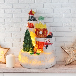 Close-up of a Christmas resin house with glowing lights, snowmen and tree ornaments