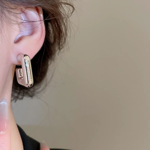 Gros plan d'une boucle d'oreille carrée minimaliste en argent sur l'oreille