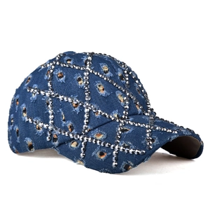 Dettaglio cappello baseball in denim blu effetto consumato con griglia di strass lucidi