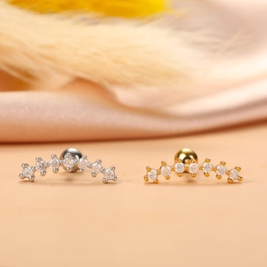 Macro detail of gold and silver curved ear piercings with shimmering zircon stones