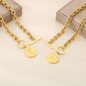 Detailed macro view of gold T-bar toggle clasp necklaces with religious saint coin pendants