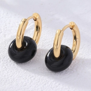 Detail of gold donut earrings featuring black natural stone pendants in a macro view