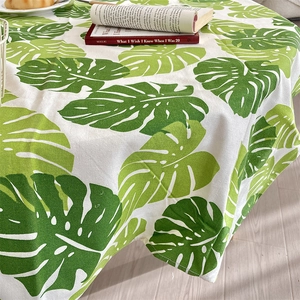 Detail of cotton linen tablecloth featuring green monstera leaf print in Nordic style