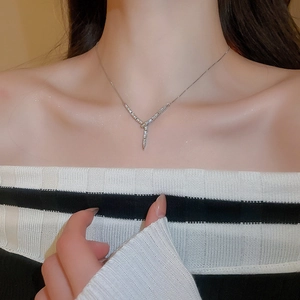 Close-up of sparkling zircon snake-shaped Y-necklace on woman's collarbone