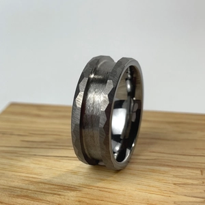 Detail of a tungsten steel ring blank with hammered texture and brushed finish on wood