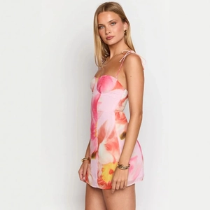 Détail de mini robe rose à imprimé floral avec fines bretelles et coupe ajustée