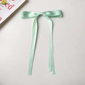 Detail of mint green satin ribbon hair clip with long streamers on white background