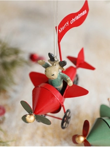 Detail of a red metal Christmas plane ornament featuring a reindeer pilot and festive flag
