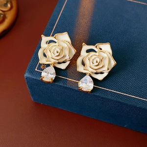 Détail de boucles d'oreilles vintage fleurs en émail blanc et zircon sur boîte cadeau bleue