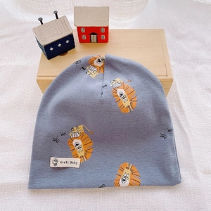 Close-up of blue-grey cotton baby hat featuring a cartoon lion print and woven label