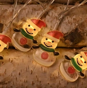 LED Christmas snowman string lights with warm yellow glow on birch bark background