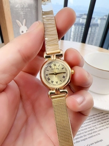 Close-up of a vintage gold women's mesh watch with a Roman numeral dial in a cozy setting