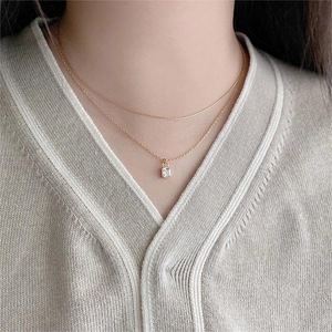 Close-up of layered gold necklace featuring a lock pendant with square zircon on a model