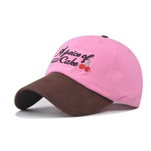 Detail of pink cotton baseball cap featuring cherry embroidery and sweets label