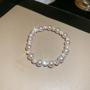 Macro view of pearl bracelet with sparkling diamond-encrusted beads on beige leather