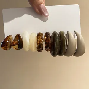 Five-pair acrylic C-shaped earring set in amber and olive green on a display card