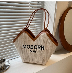 Close-up of woven straw tote bag with brown leather trim and MOBORN PARIS embroidery