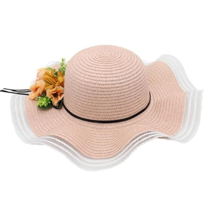 Détail d'un chapeau de paille rose avec dentelle blanche et décorations florales