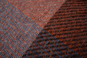 Macro shot of thick orange and navy herringbone wool blend fabric texture with soft fuzz
