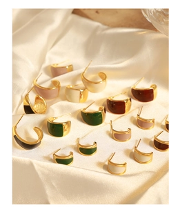 Detailed close-up of colorful enamel and gold C-shaped earrings on elegant silk fabric
