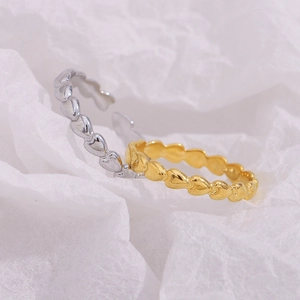 Detailed view of intertwined gold and silver heart rings on a white textured background