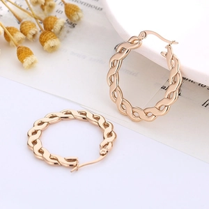 Gros plan de boucles d'oreilles créoles torsadées en or rose avec motif de corde