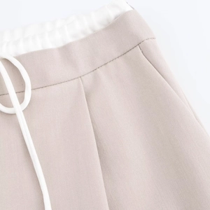 Detailed close-up of drawstring elastic waistband and side pocket on twill trousers