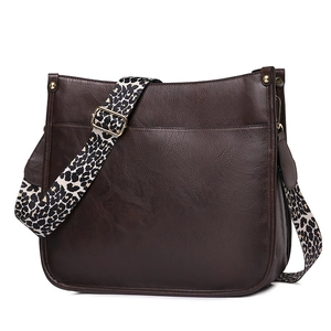 Detail view of dark brown faux leather tote bag with a trendy leopard print strap