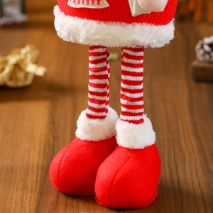 Detail of Christmas doll with striped knit legs and red felt shoes on wooden table