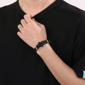 Braided black leather rope bracelet with gold magnetic buckle shown on a model wrist