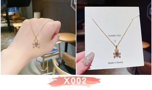 Dettaglio della collana con orsetto dorato, cuore viola e cristalli su cartoncino