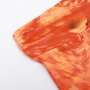 Detailed view of the vibrant orange and red artistic gradient print on glossy fabric