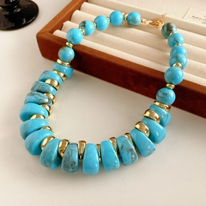 Détail macro des perles bleu marbré et des intercalaires dorés sur un collier vintage