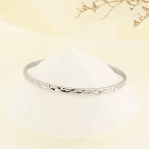 Close-up of silver titanium steel bracelet with diamond-cut geometric patterns on a stand