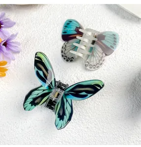 Detail view of two butterfly acrylic hair claws with blue and white marble textures