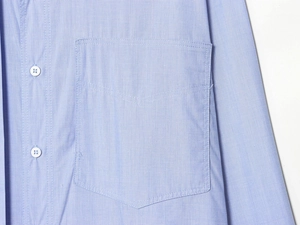 Detail of light blue cotton shirt showing front pocket and white button stitching