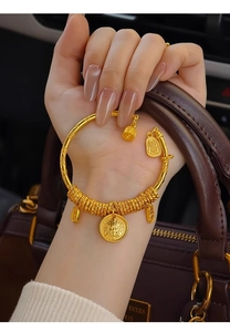 Detail of 24k gold plated open bangle featuring vintage charms and lucky inscriptions