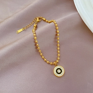 Detailed view of a gold-plated stainless steel bead bracelet on champagne satin fabric