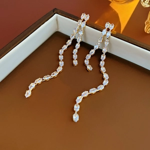 Detailed macro view of gold tassel earrings with zircon crystals on a jewelry box