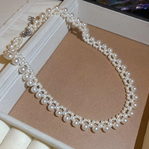 Detail of woven freshwater pearl necklace with alternating sizes and lace-like texture