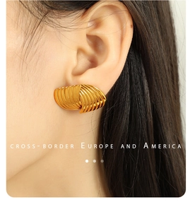 Macro shot of gold striped texture earrings worn by a model in luxury metal style