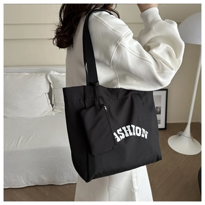 Close-up of black fashion tote bag with white lettering and matching zipper pouch