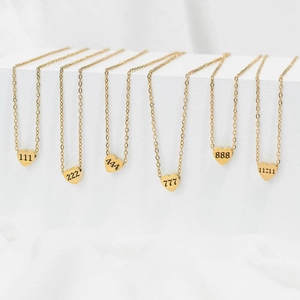 Detailed close-up of gold angel number heart pendants on minimalist O-chains