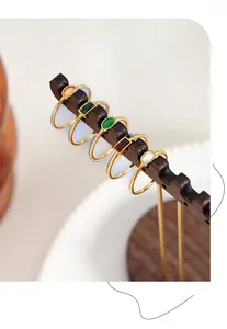 Detail view of five vintage gold rings with emerald and oval stones on a wooden stand