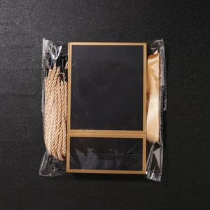 Unassembled black paper gift bag kit with gold ribbon and rope handles in packaging