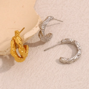 Dettaglio orecchini a C in oro 18K e argento con finitura martellata effetto lava