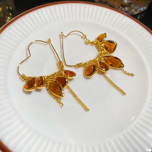 Macro shot of 18K gold heart earrings with amber crystals and elegant chain tassels