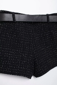 Détail du tissu en tweed noir avec fil métallique argenté et une ceinture en cuir